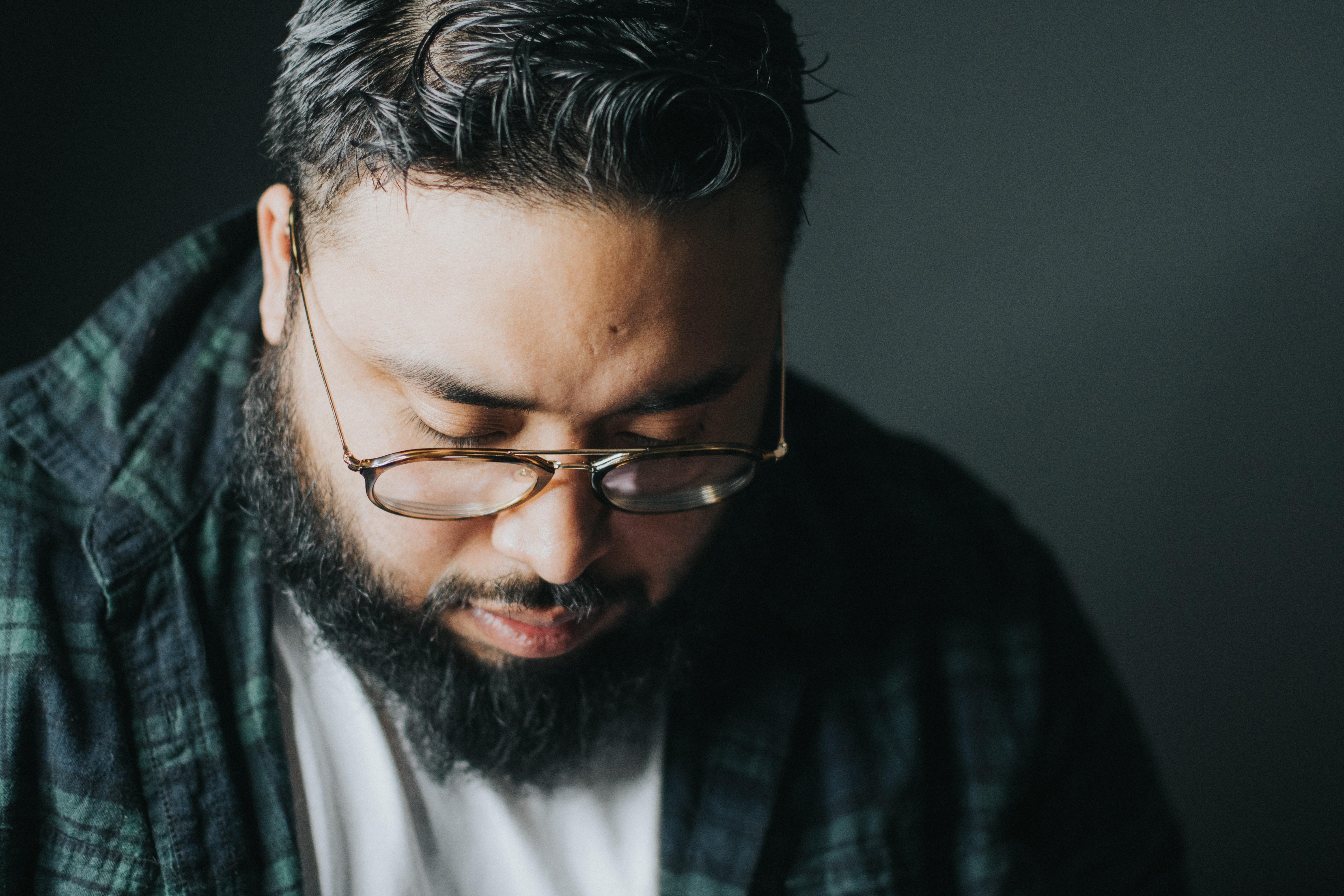 Latinx man looking down. Photo by Hermes Rivera on Unsplash.